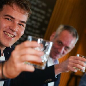 Zwei Herren verschiedener Generationen in geselliger Runde mit einem guten Tröpfchen zum Anstoßen beim Gentlemen`s Club.