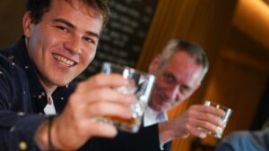 Zwei Herren verschiedener Generationen in geselliger Runde mit einem guten Tröpfchen zum Anstoßen beim Gentlemen`s Club.