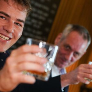 Zwei Herren verschiedener Generationen in geselliger Runde mit einem guten Tröpfchen zum Anstoßen beim Gentlemen`s Club.