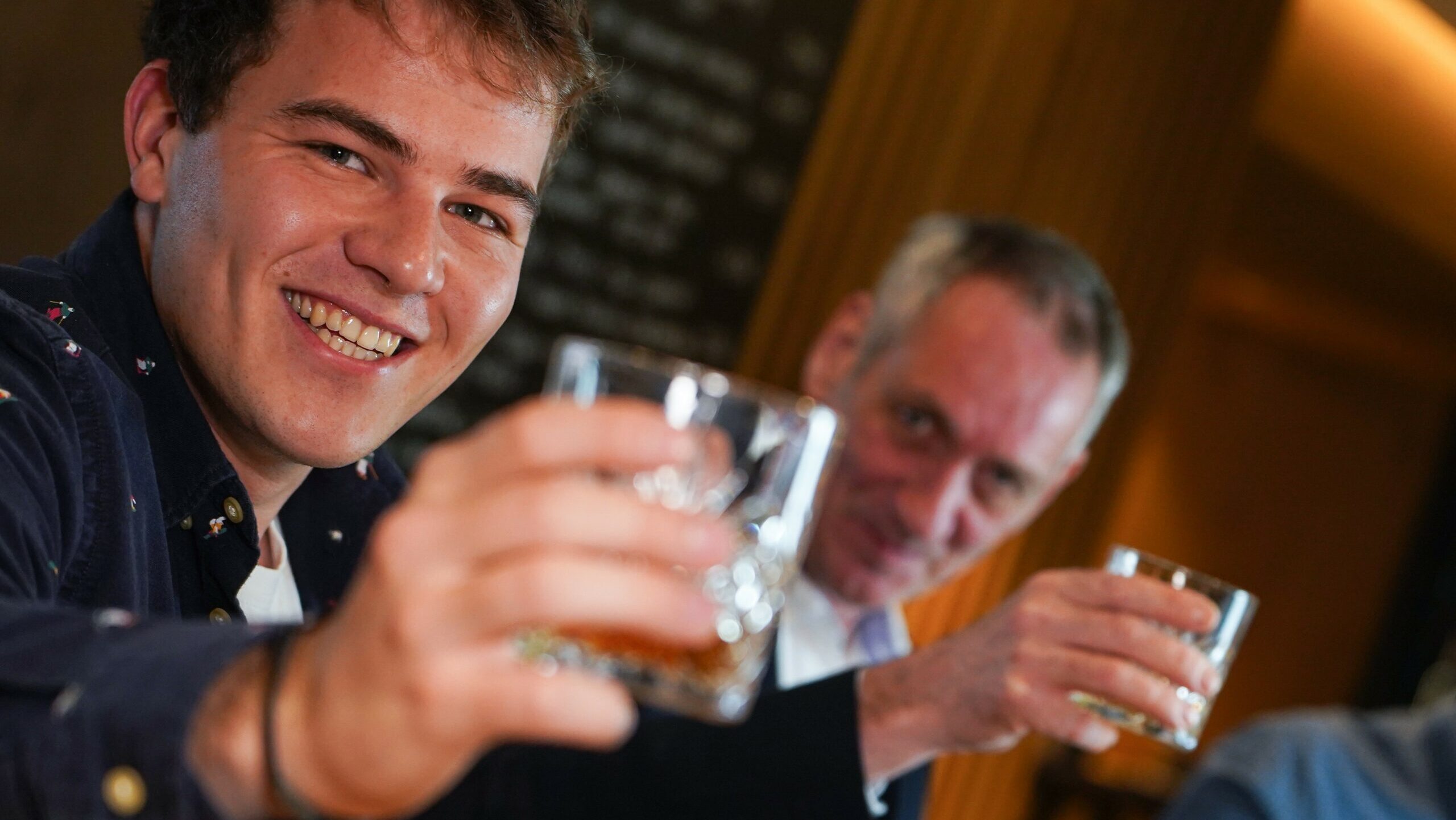 Zwei Herren verschiedener Generationen in geselliger Runde mit einem guten Tröpfchen zum Anstoßen beim Gentlemen`s Club.